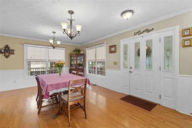 a dining room with wooden floor a chandelier a wooden table and chairs