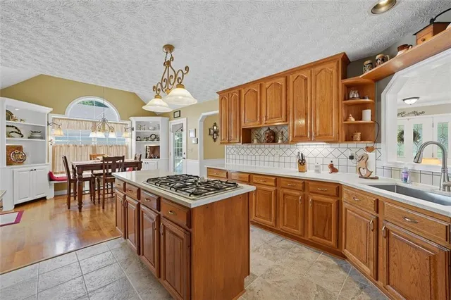 a kitchen with stainless steel appliances granite countertop a stove a sink dishwasher and a dining table with cabinets