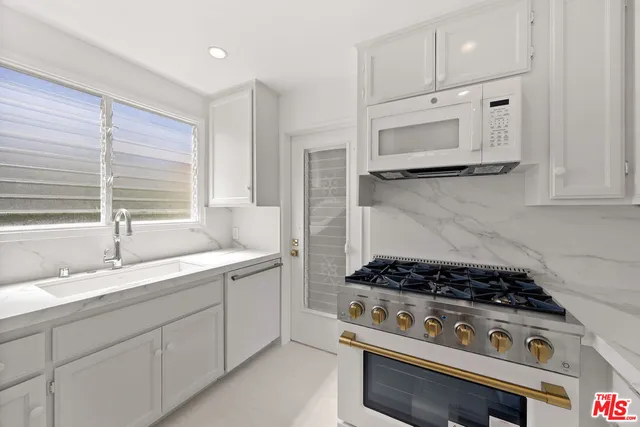 a kitchen with white cabinets and appliances