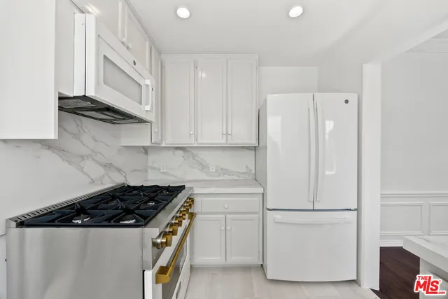 a white kitchen with stainless steel appliances and white cabinets