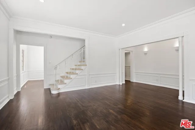 a view of an empty room with wooden floor and stairs