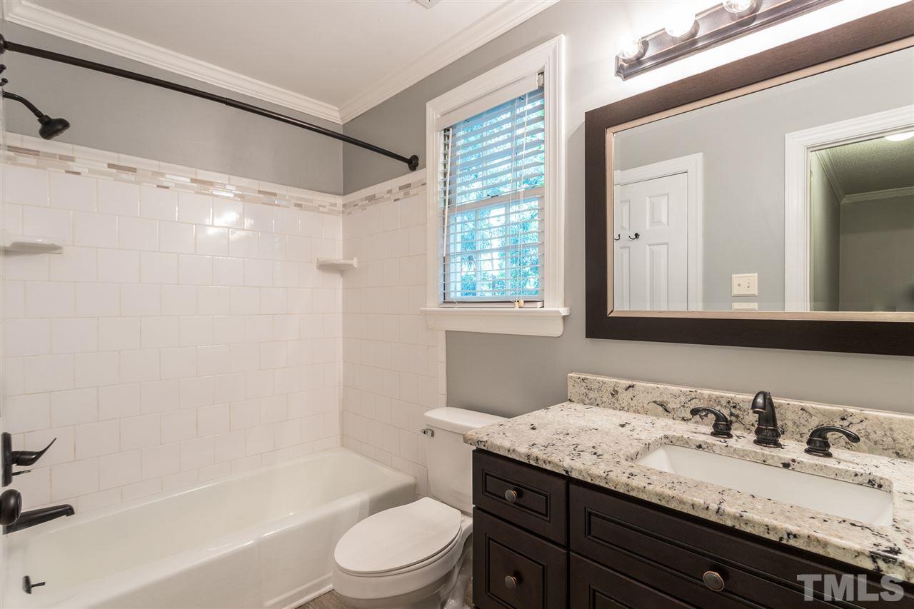 4513 Lancashire Drive Raleigh, NC 27613 - Photo 22 of 25 a bathroom with a granite countertop sink toilet a large mirror a bathtub and shower