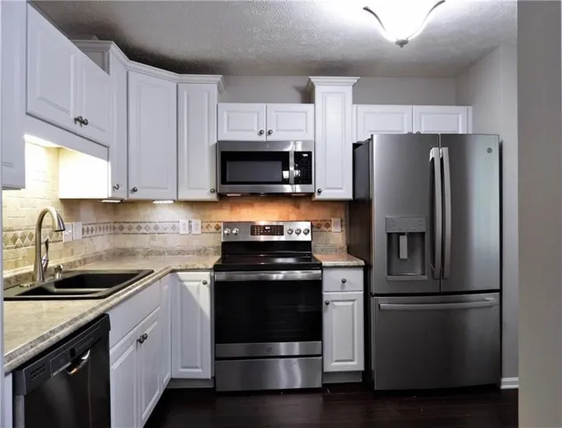 a kitchen with refrigerator a microwave a sink and cabinets