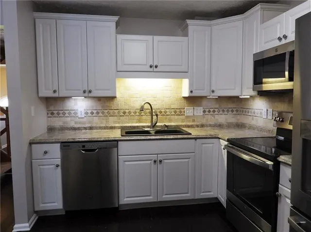 a kitchen with granite countertop white cabinets and black appliances