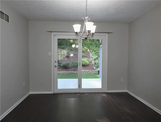 a view of a room with wooden floor chandelier and a window