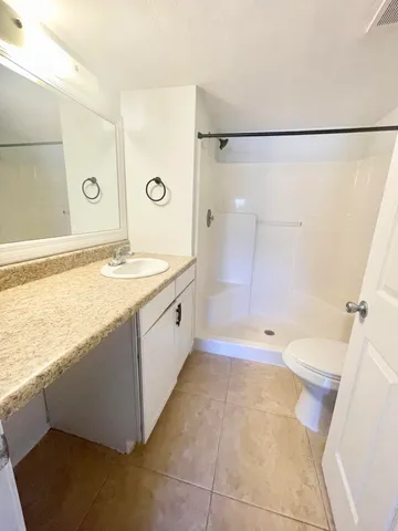a bathroom with a granite countertop sink a toilet and shower