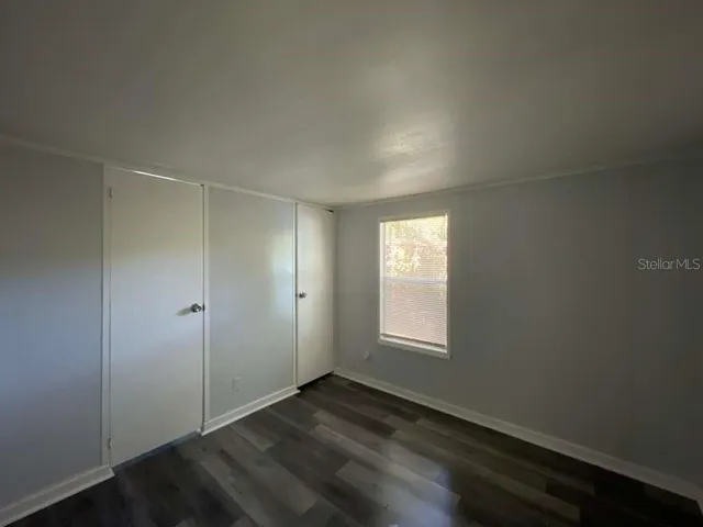 an empty room with wooden floor and window