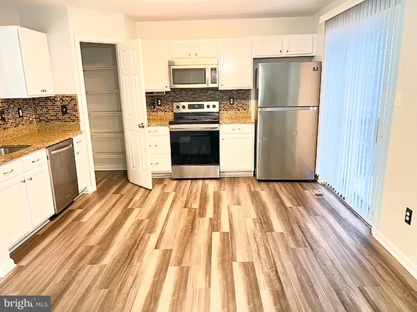 a kitchen with a refrigerator a stove top oven and a dishwasher with wooden floor