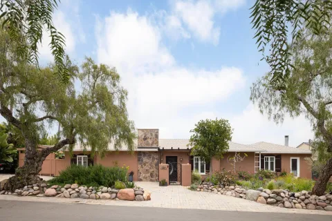 a front view of a house with a garden and tree