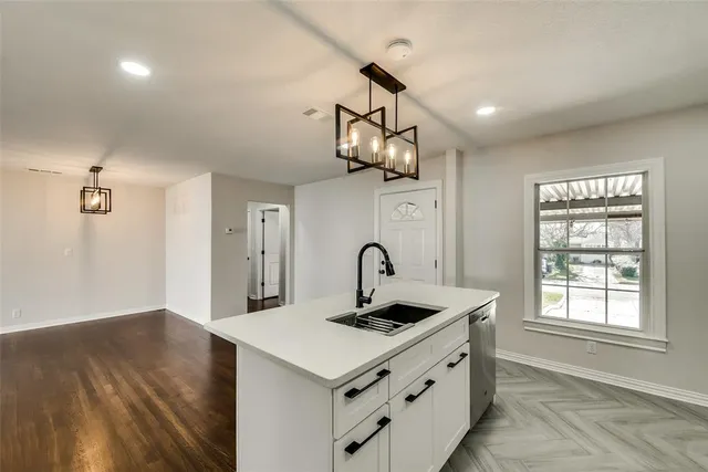 a kitchen with a sink dishwasher a stove and a dining table with wooden floor
