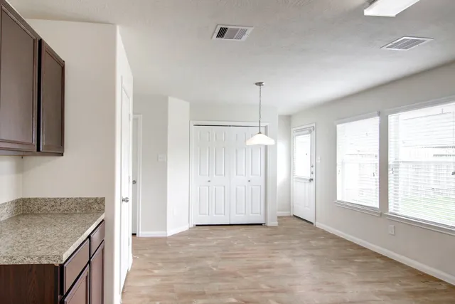 a view of an empty room with a kitchen and a window