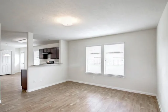 an empty room with a window and a kitchen