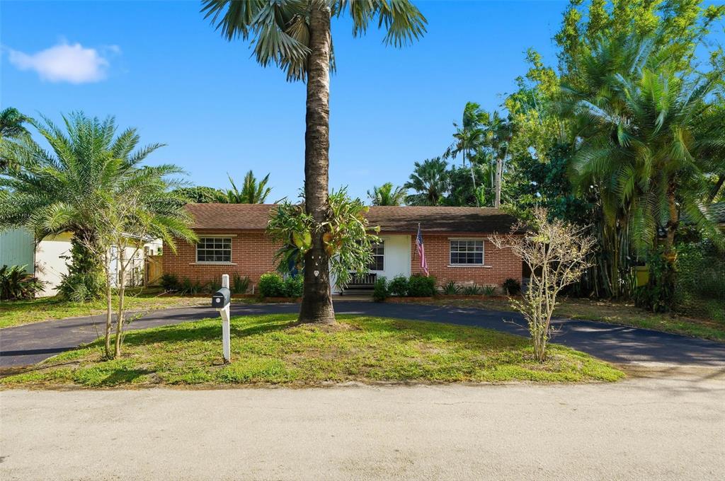 a view of a house with a yard and palm trees