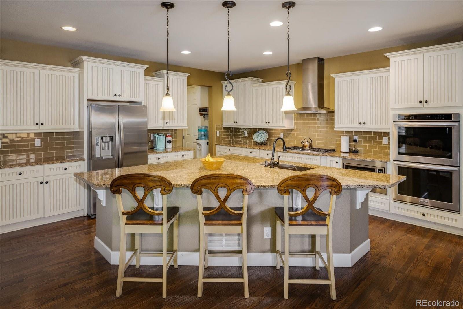 a kitchen with stainless steel appliances kitchen island granite countertop a dining table chairs sink and cabinets