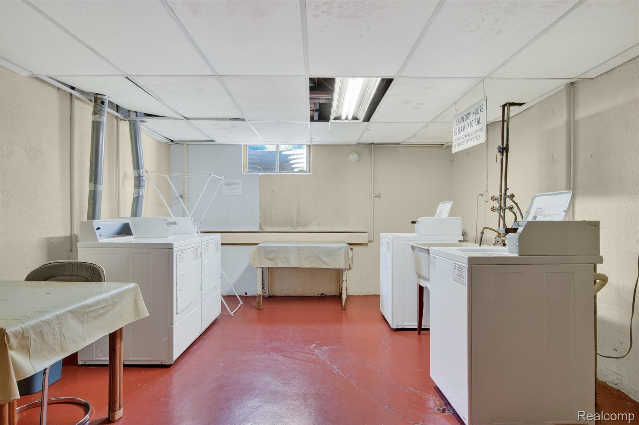 24111 Meridian Road, Unit 116 Grosse Ile, MI 48138 - Photo 23 of 26 Laundry facility featuring multiple washer and dryer units, a utility sink, and durable red flooring