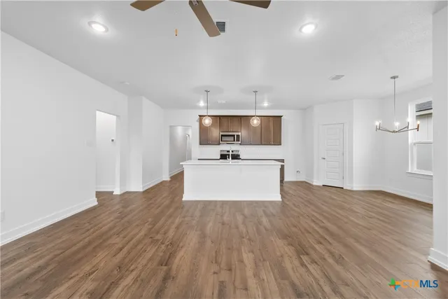 a view of kitchen with microwave a stove and white cabinets