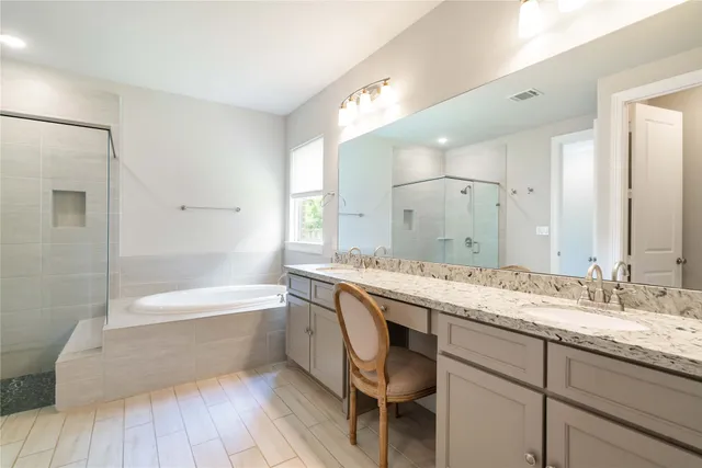 a bathroom with a granite countertop bathtub a sink and a large mirror