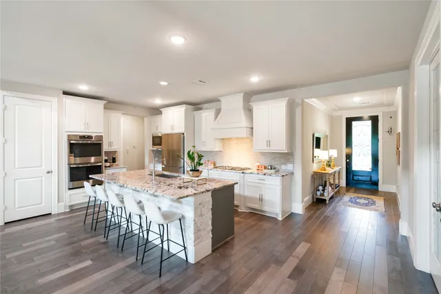 a kitchen with stove a refrigerator and a dining table with wooden floor