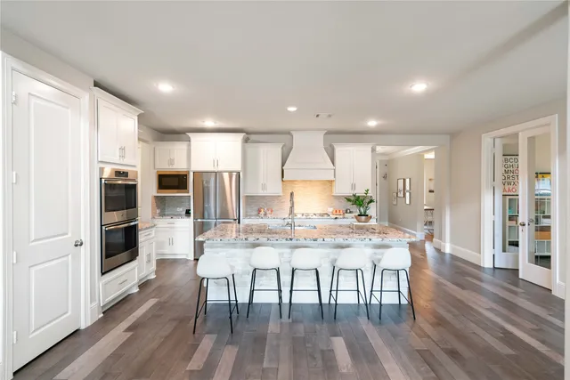 a kitchen with stainless steel appliances a dining table chairs stove refrigerator and wooden floor
