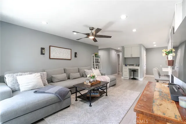 a living room with furniture kitchen view and a chandelier