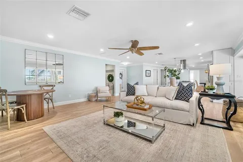 a kitchen with stainless steel appliances a sink a stove a refrigerator and chairs