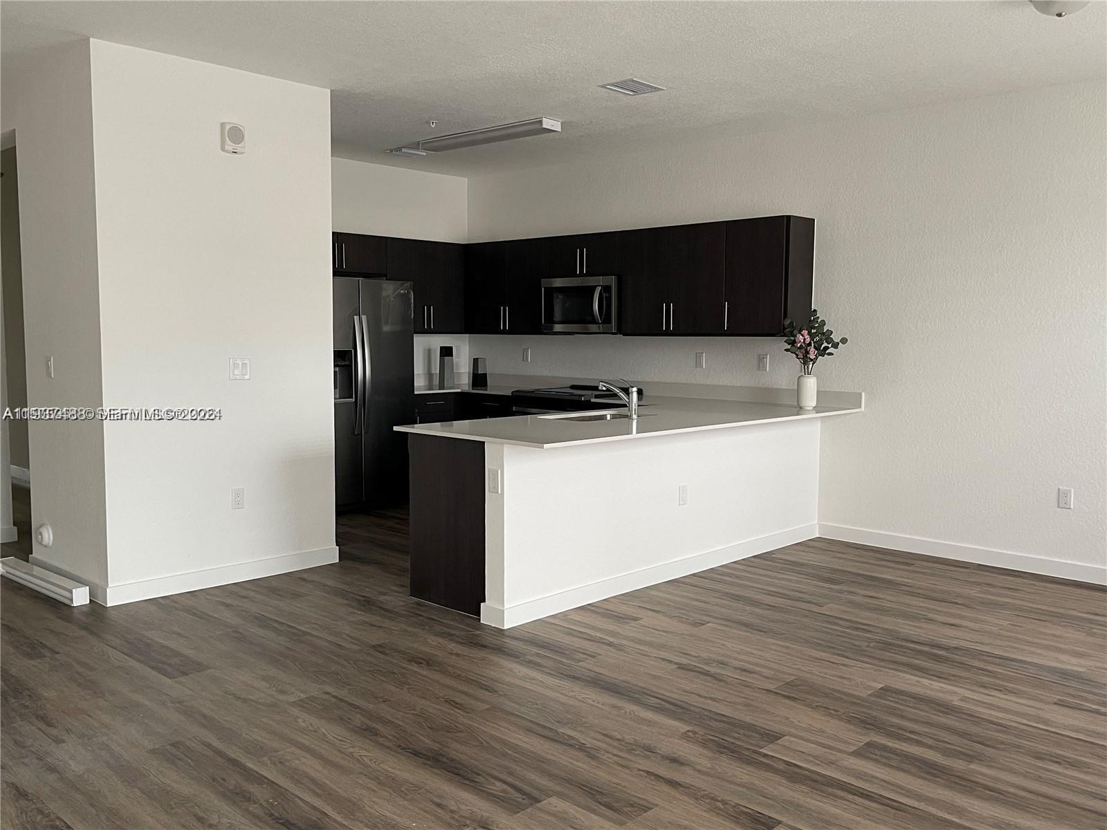 15520 Southwest 136th Street, Unit 104 Miami, FL 33196 - Photo 5 of 13 a kitchen with stainless steel appliances a sink and a microwave