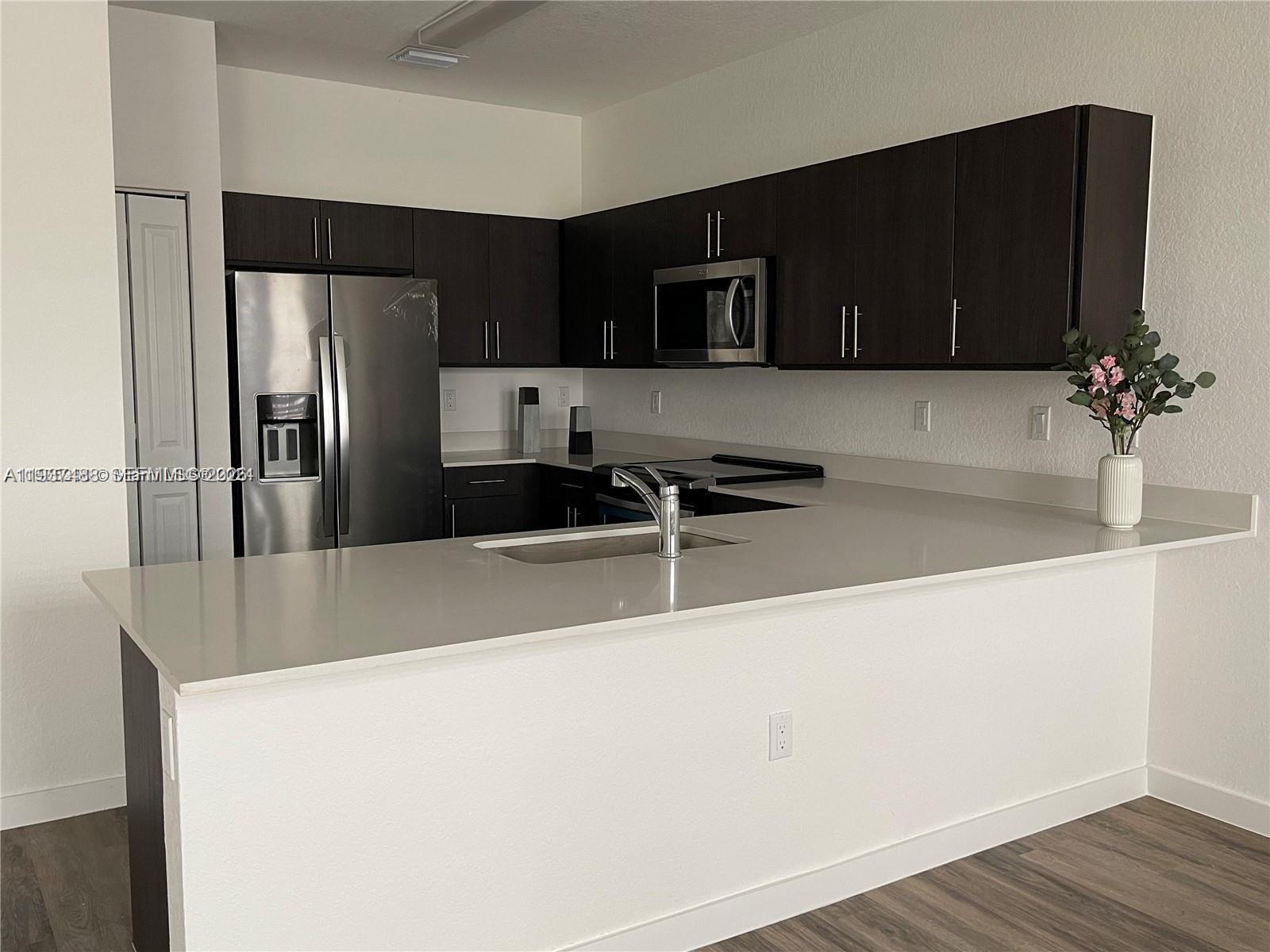 15520 Southwest 136th Street, Unit 104 Miami, FL 33196 - Photo 6 of 13 a kitchen with stainless steel appliances a refrigerator and a sink