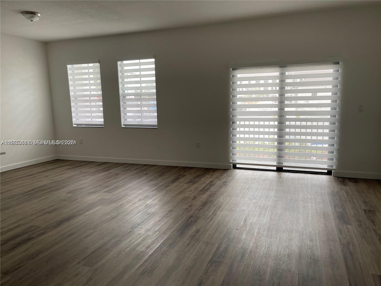 15520 Southwest 136th Street, Unit 104 Miami, FL 33196 - Photo 7 of 13 an empty room with wooden floor and windows