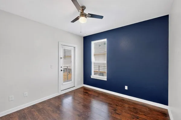 a view of an empty room with a window and wooden floor
