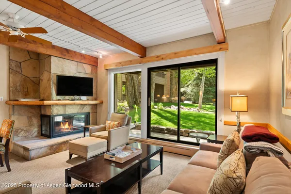 a living room with furniture a flat screen tv and a floor to ceiling window