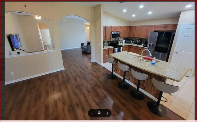 a living room with stainless steel appliances furniture and a wooden floor