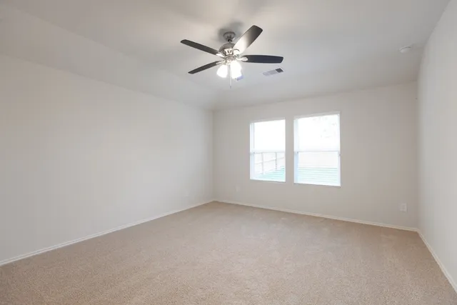 an empty room with a window and a fan