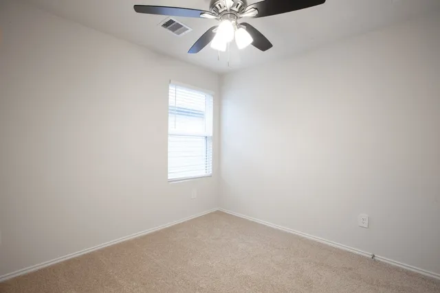an empty room with a window and a fan