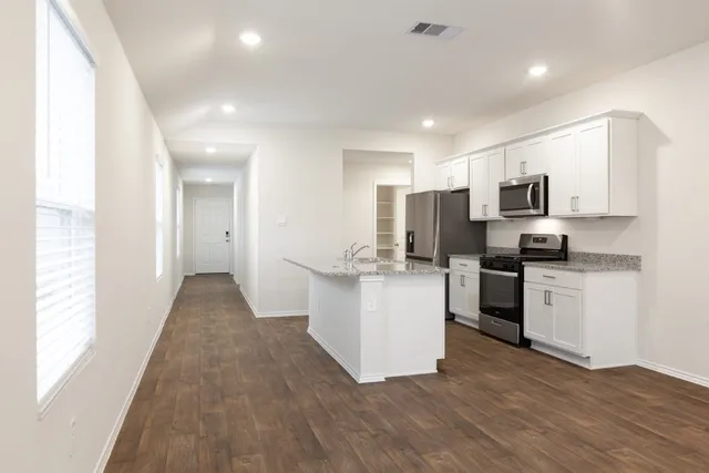a kitchen with granite countertop white cabinets and stainless steel appliances
