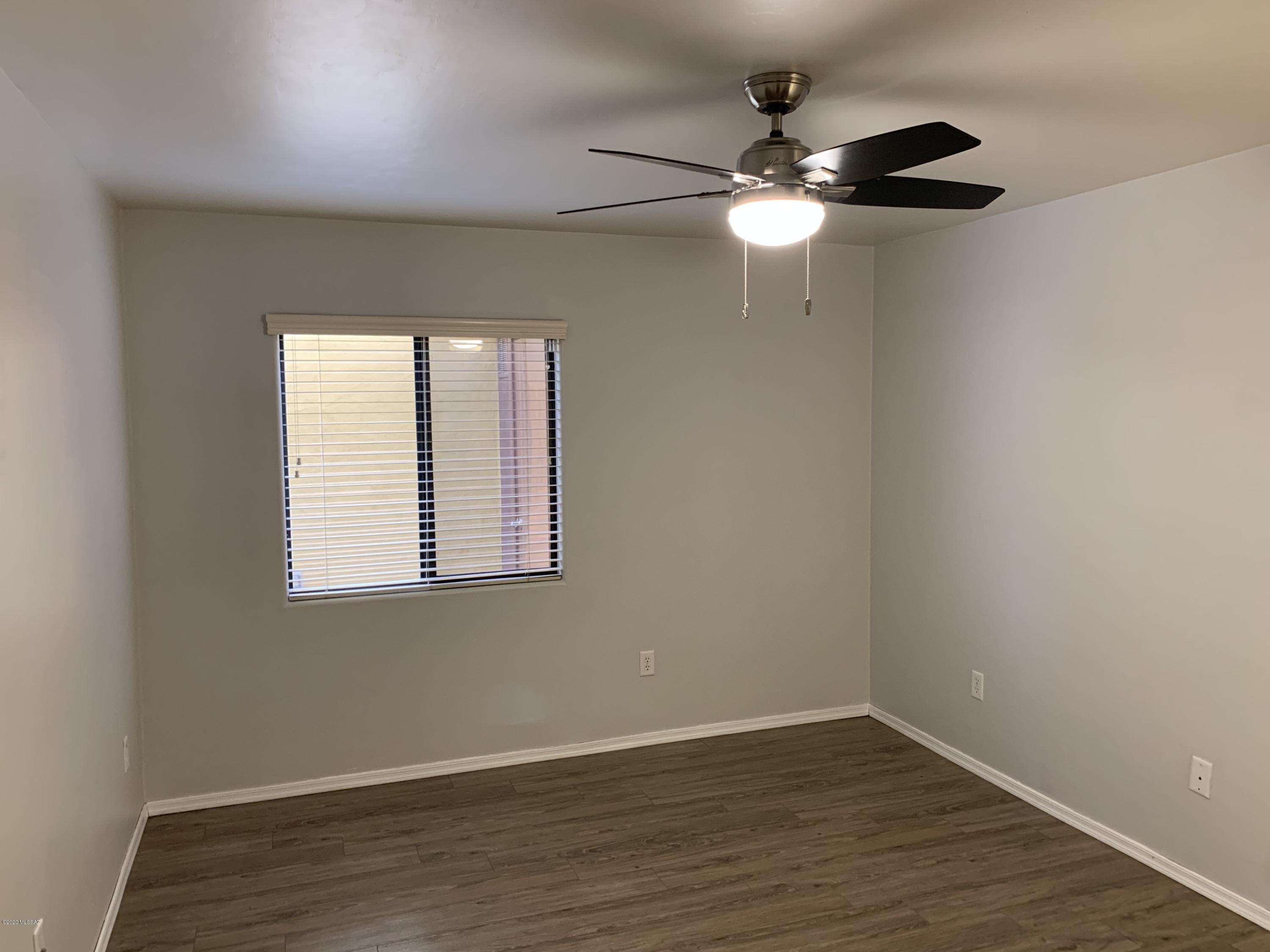 4181 North Fortune Loop Tucson, AZ 85719 - Photo 14 of 39 an empty room with wooden floor fan and windows