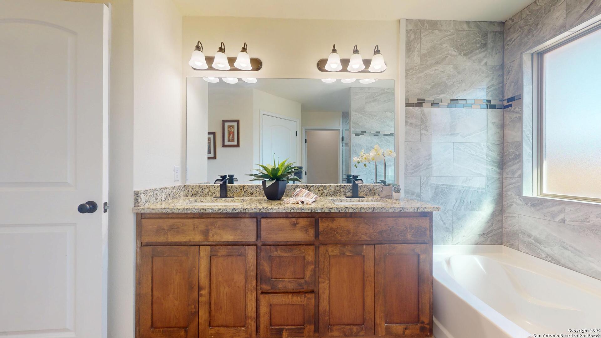 3992 Fm 1784 Pleasanton, TX 78064 - Photo 23 of 38 a bathroom with a granite countertop sink a large mirror and a bathtub