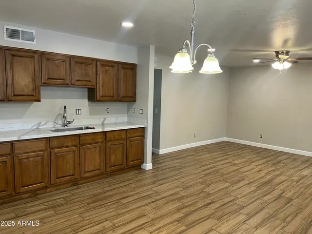 a kitchen with a sink chandelier and wooden cabinets