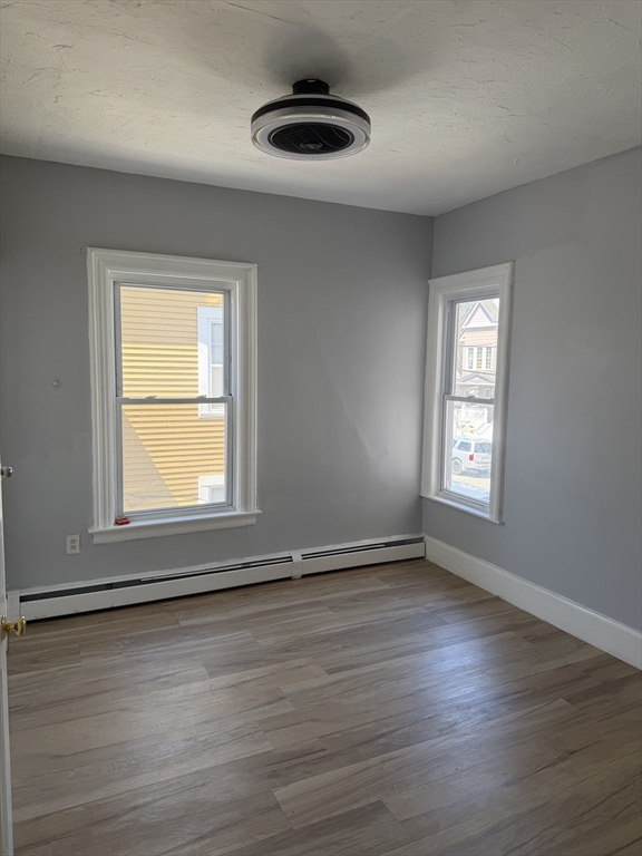 40 Rogers Avenue, Unit 2 Lynn, MA 01902 - Photo 12 of 15 an empty room with wooden floor and windows