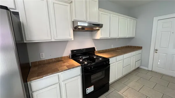 a kitchen with granite countertop white cabinets and black appliances
