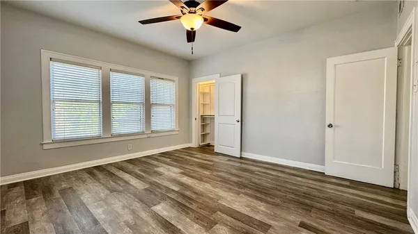 a view of an empty room with wooden floor and a window