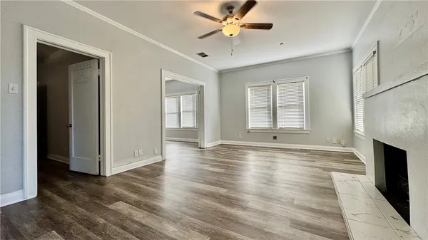 a view of an empty room with window and wooden floor