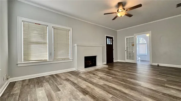 a view of a livingroom with a fireplace a ceiling fan and windows