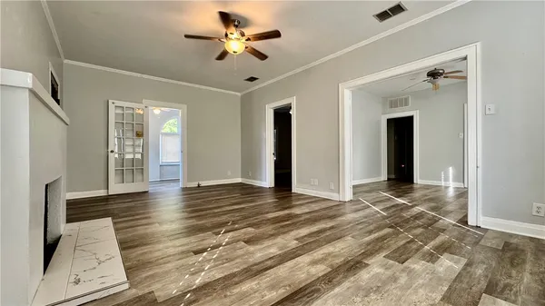 a view of an empty room with wooden floor and a ceiling fan
