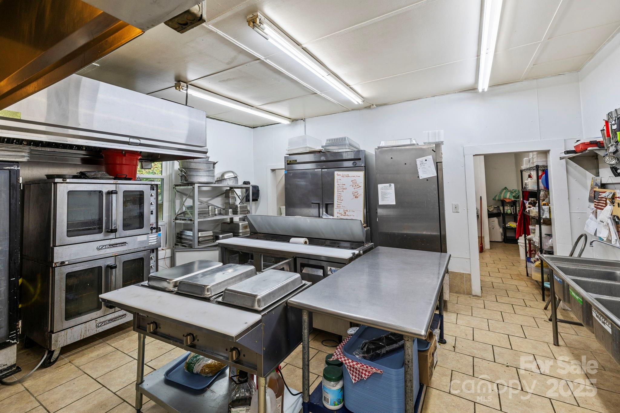 1196 North Country Club Road Brevard, NC 28712 - Photo 14 of 48 a living room with stainless steel appliances kitchen island granite countertop a table chairs and a refrigerator