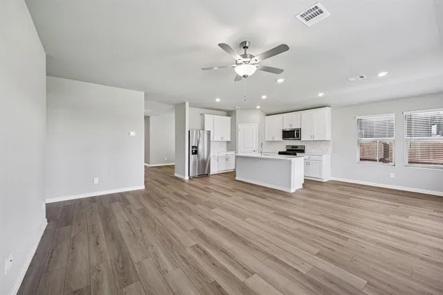 a view of a kitchen with a sink a refrigerator a ceiling fan and wooden floor