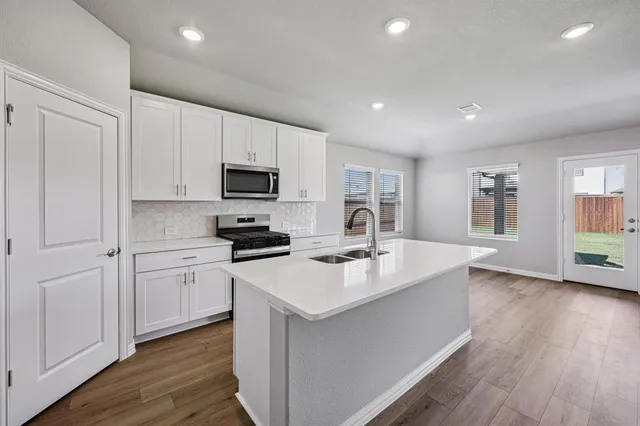 a kitchen with a sink stainless steel appliances a counter top space and cabinets
