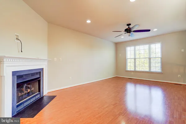 a view of an empty room with wooden floor fireplace and a window
