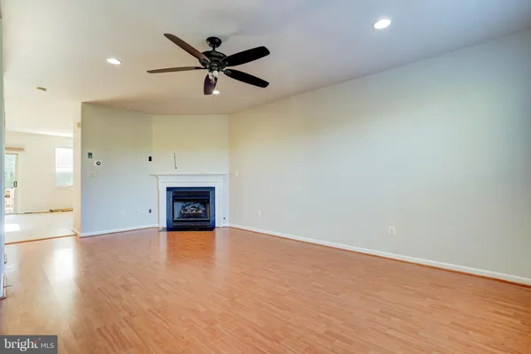 an empty room with wooden floor ceiling fan and windows
