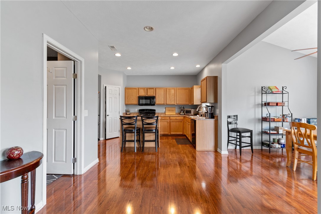4467 Ridgestone Way Medina, OH 44256 - Photo 7 of 31 Kitchen featuring black appliances, dark hardwood / wood-style flooring, a kitchen breakfast bar, and light brown cabinetry