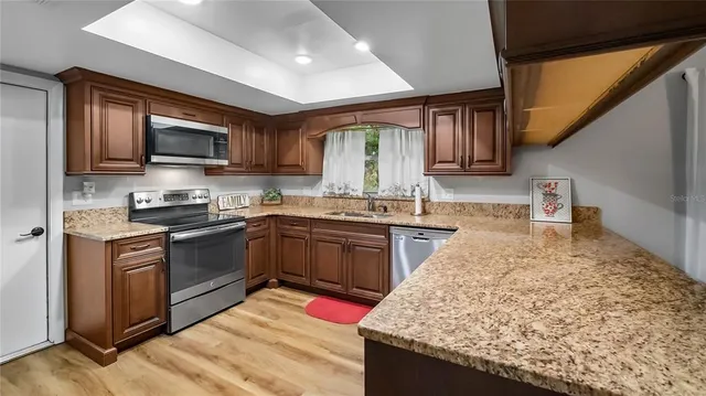 a kitchen with granite countertop wooden cabinets a sink and stainless steel appliances